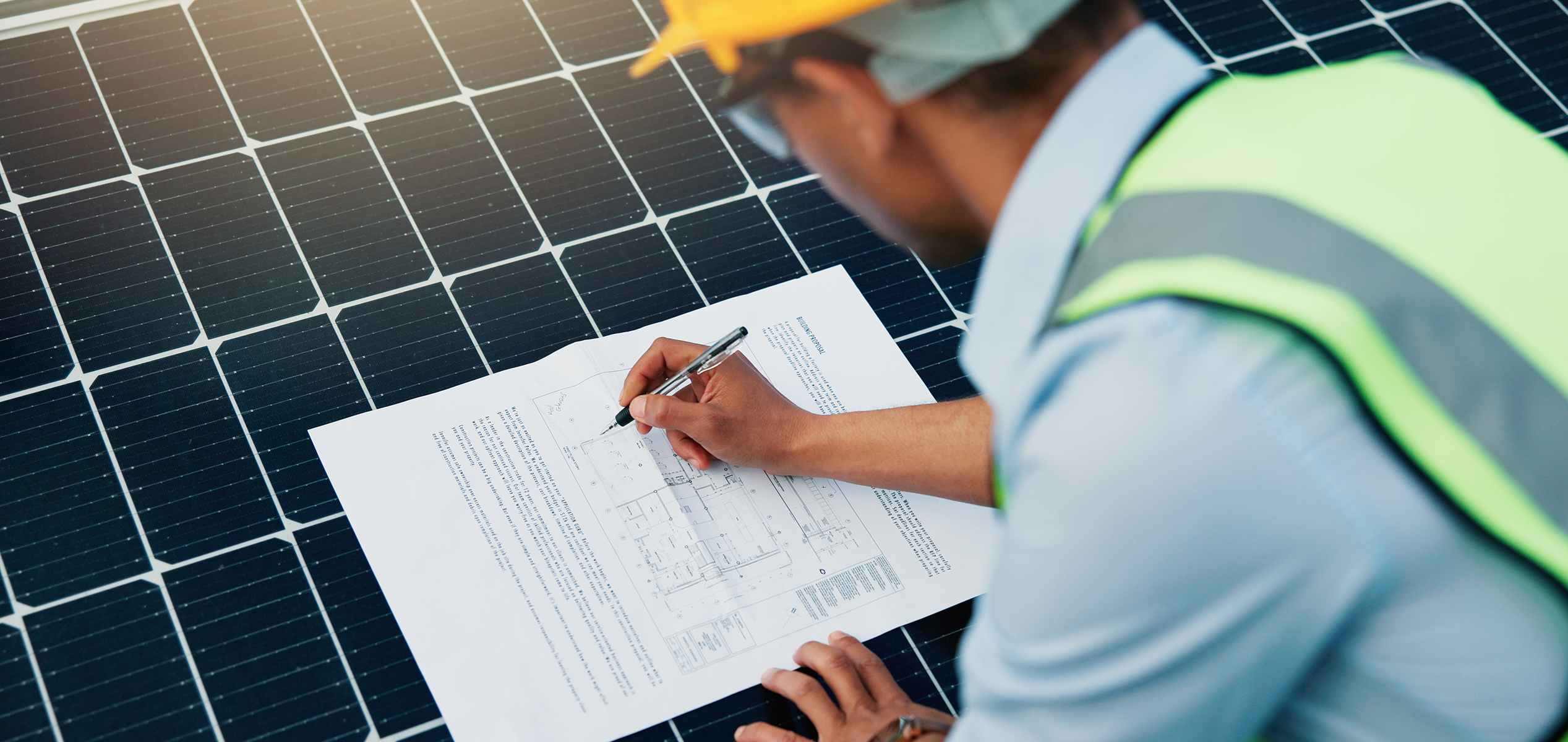 Solar technician checking panels and system blueprints